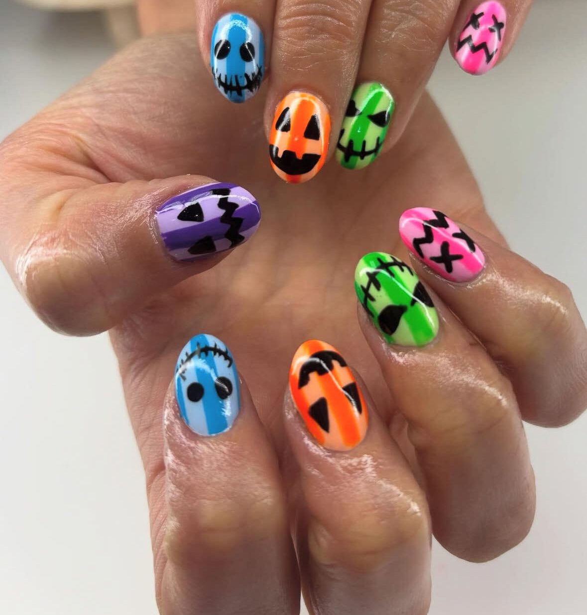 Hand-painted Halloween faces on neon-striped nails